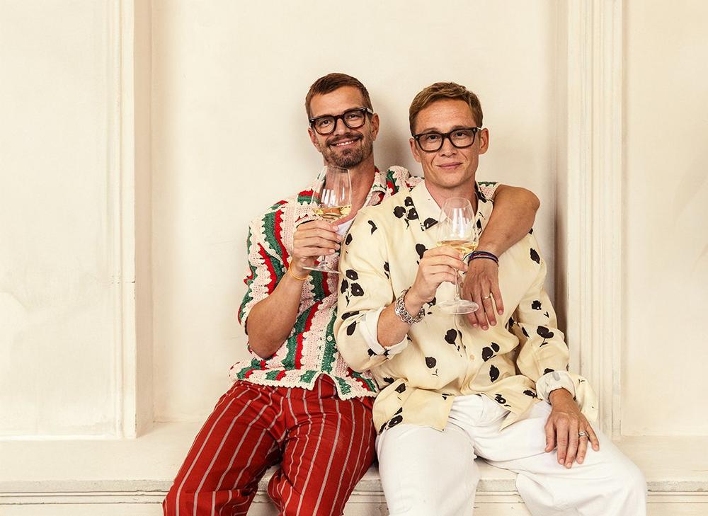 Joko und Matthias feiern den Frühling mit einem Freund im Arm und einem Glas Wein in der Hand